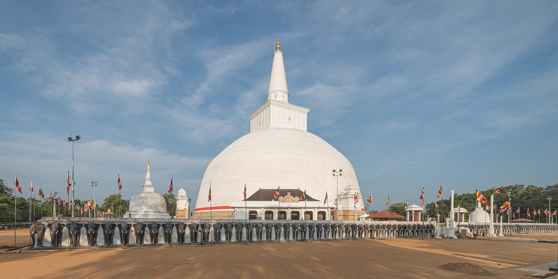 The white dome of the Ruwanwelisāya stūpa at Anurādhapura rising above its elephant-wall terrace under a wide sky.